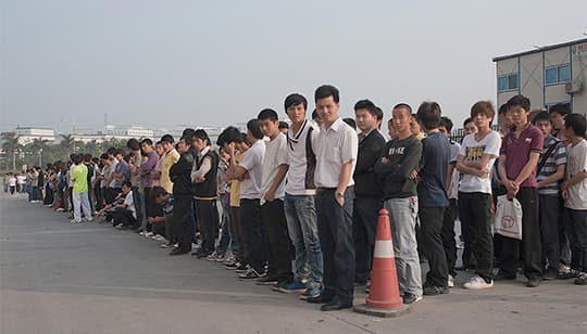 Morgon i Shenzhen i Kina. 7000 arbetssökande i kö för att få jobba på Foxconn som tillverkar Apples produkter. Låga löner lockade hit industrin – men nu stiger löner i Kina och företagen tvingas tänka om. Foto: GERHARD JÖREN