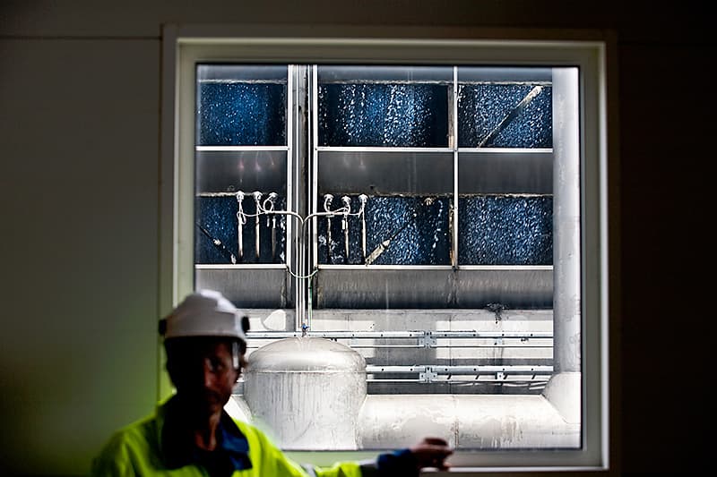 Jörgen Agebjörn i den stora kondensturbinhallen, från vilken den använda ångan leds till kyltornet, som syns genom fönstret, för återvinning. Foto: JAN NORDSTRÖM