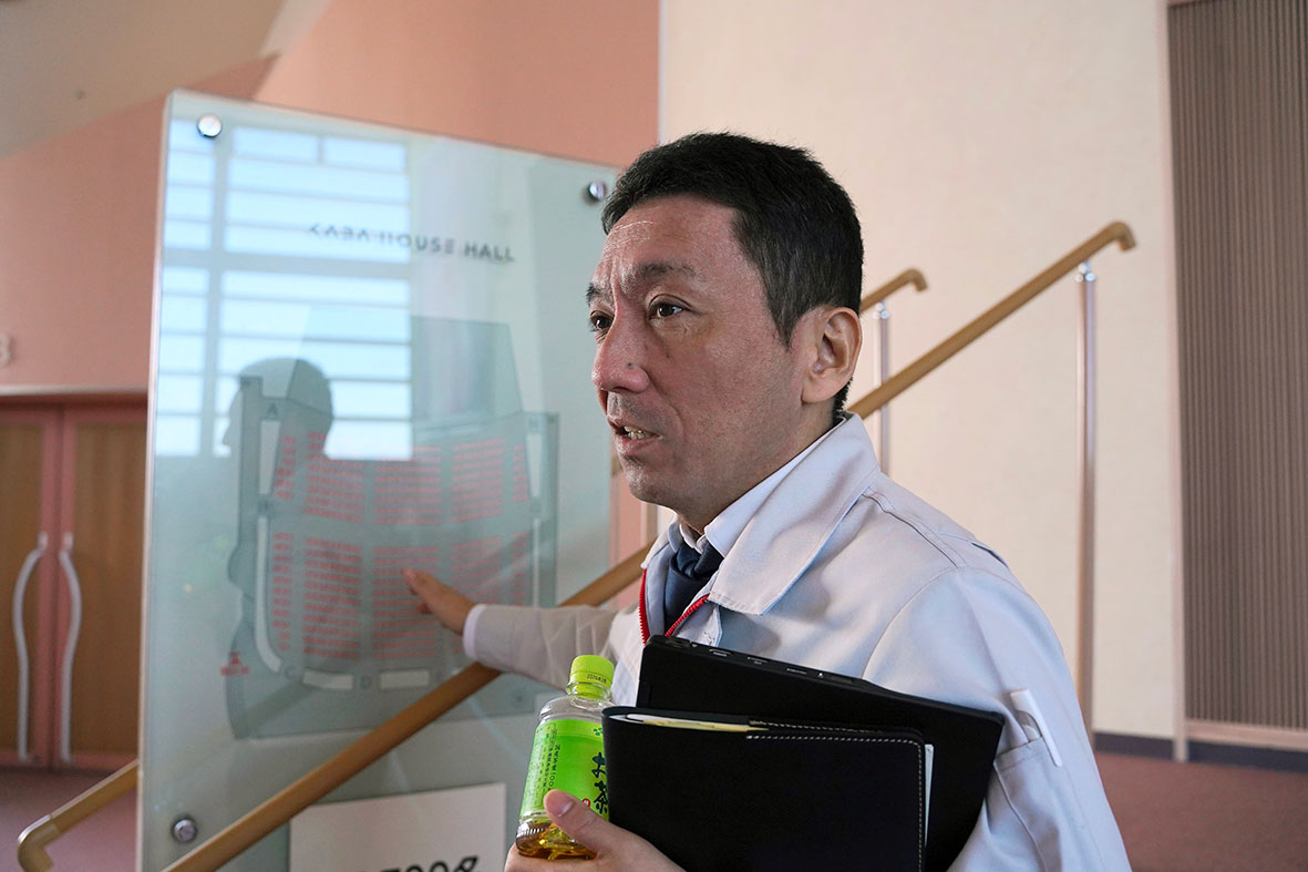 Hiroki Akiyama, även han generalsekreterare på Toyotafacket, pekar på skylten över aulan högst upp i flodhästhuset och berättar att en anställd gifte sig där i höstas och bjöd in sina kollegor. Foto: Peter Schwartz