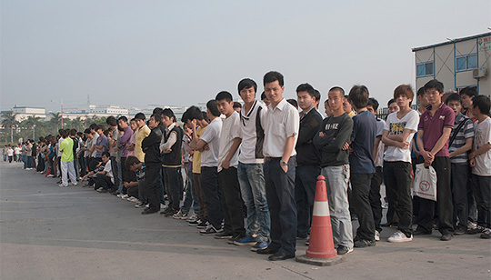 Morgon i Shenzhen i Kina. 7000 arbetssökande i kö för att få jobba på Foxconn som tillverkar Apples produkter. Låga löner lockade hit industrin – men nu stiger löner i Kina och företagen tvingas tänka om. Foto: GERHARD JÖREN