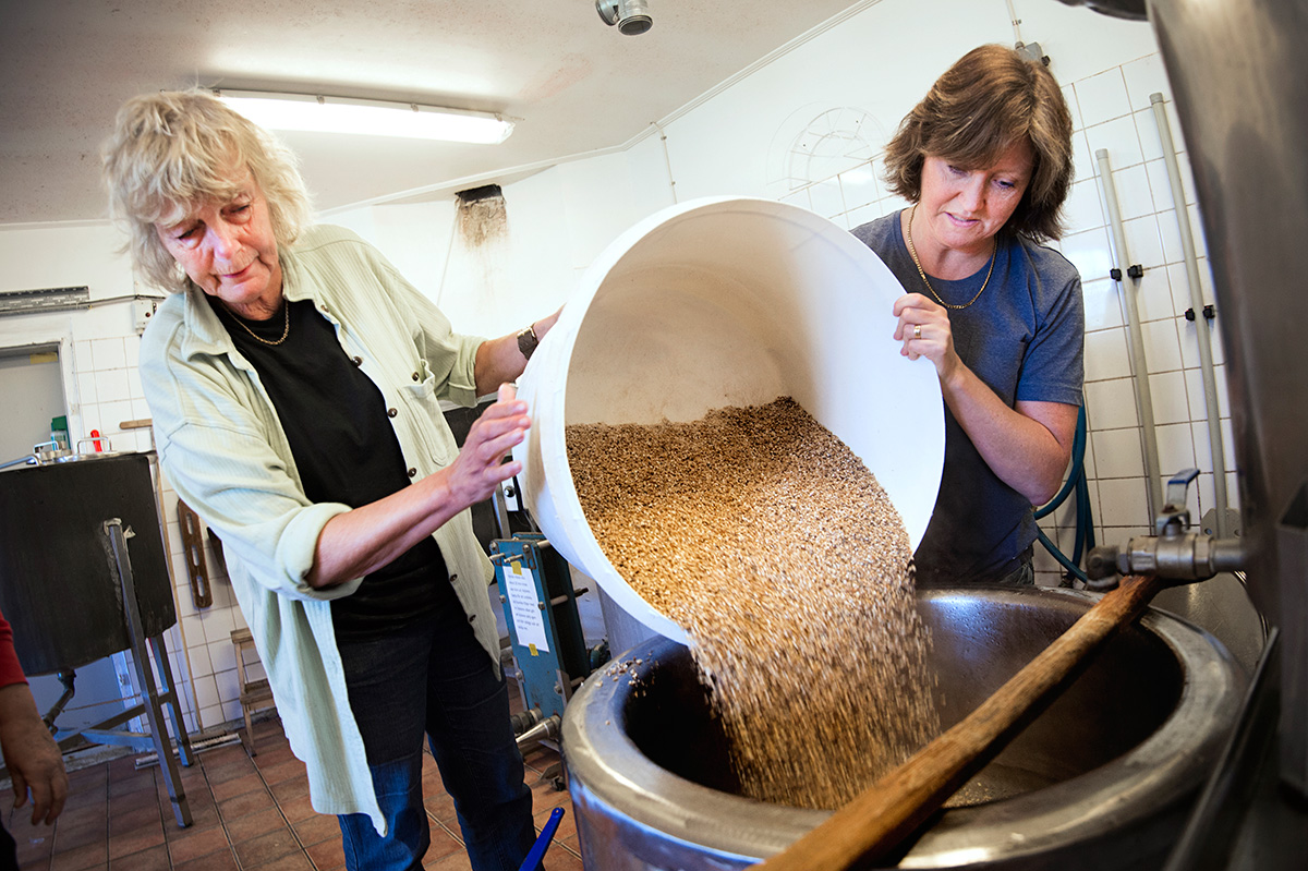Anita och Britt vid mäskkaret, där 78-gradigt vatten hälls över den krossade malten …
